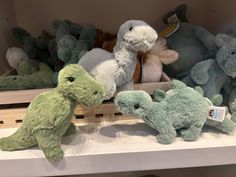 several stuffed animals are on display in a toy store, one is green and the other is blue