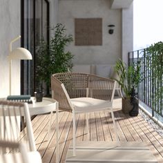 two chairs and a table on a wooden deck with potted plants in the background