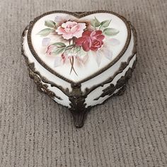 a heart shaped trinket with flowers painted on the front and sides, sitting on a carpeted floor