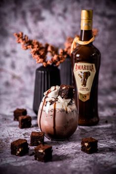 an ice cream sundae with caramel and whipped cream in it next to a bottle of amarul