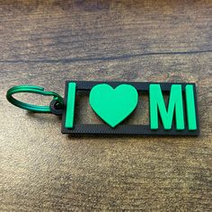 a keychain shaped like a heart with the word i love m on it