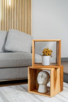 a vase with flowers in it sitting on top of a wooden box next to a couch