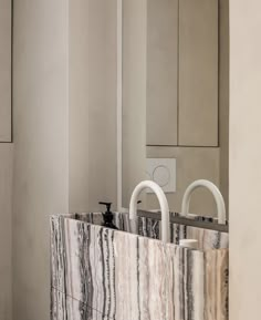 two white handles on a marbled counter in a room with mirrors and cupboards