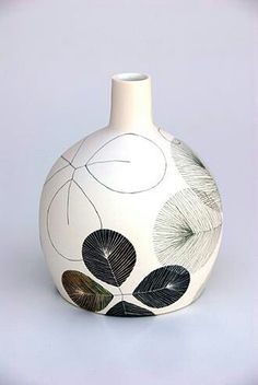 a white vase with black and green leaves on it