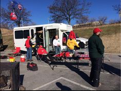 some people are standing in front of a white truck with red and yellow hats on