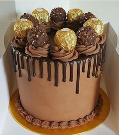 there is a chocolate cake that has been decorated with gold and chocolate candies on top