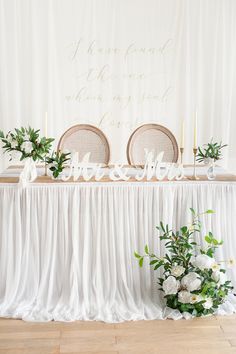 the table is set up with white flowers and greenery