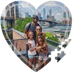 a man and two girls are posing in front of a heart shaped jigsaw puzzle