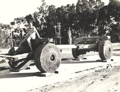 an old black and white photo of a man sitting on top of two large wheels