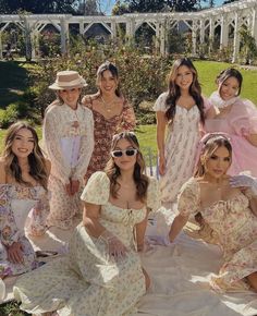 a group of young women in dresses and hats posing for a photo on a blanket