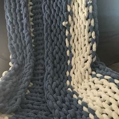 a blue and white knitted blanket sitting on top of a bed