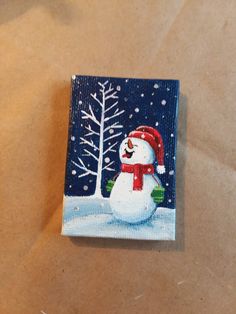 a painting of a snowman on a piece of paper with trees in the background