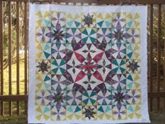 a colorful quilt hanging on a fence