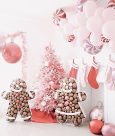 a pink christmas tree decorated with gingerbread man and woman cookies in front of a fireplace