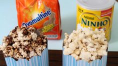 two blue striped cups filled with popcorn next to some yogurt and other snacks