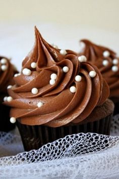 three cupcakes with chocolate frosting and white sprinkles on top