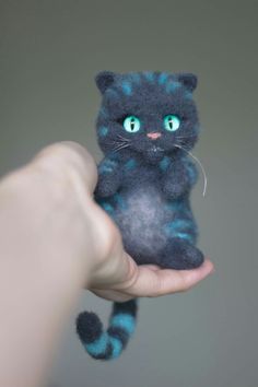 a hand holding a small blue and black cat