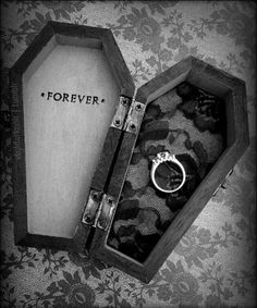 an open box with a ring inside on a floral wallpapered background that says forever