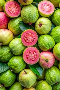 a pile of green and pink fruit with leaves