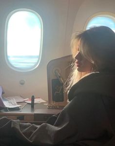 a woman sitting in an airplane looking out the window