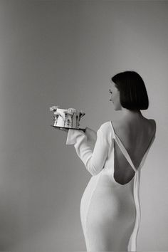 a woman in a white dress holding a piece of cake