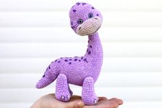 a small purple crocheted giraffe sitting on top of someone's hand