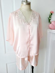 Vintage 2 piece pink satin pajama set. Top features sheer flowy sleeves and lace detail at neckline with tiny pearl accents. Pearl buttons. Elastic waistband on shorts. Excellent vintage condition.  Size: XL (see measurements) Material: poly satin Condition: excellent vintage  Label: Dora C.  //Measurements with item laying flat,  in inches// (Top) Shoulder: 19 Chest: 22 Length: 21 (Bottom) Waist: 12, stretches to 16 Hip:23 Inseam: 3 For best fit comparison, I suggest you measure a garment you own that you know fits you well and compare to measurements given here.  Alternatively you can take the bust, waist, and hip flat measurements from above and double them, then compare to your body measurements (including a little extra wiggle room depending on the fit you prefer).  All items are vint Vintage Ballet, Satin Pajama Set, Pyjama Satin, Satin Pajama, Ballet Pink, Flowy Sleeves, Satin Pyjama Set, Satin Pajamas, Silk Pajamas