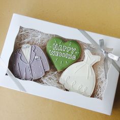 three decorated cookies in a gift box with the words happy wedding written on them,