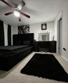 a bedroom with a black bed, mirror and ceiling fan