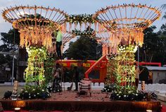 an outdoor wedding setup with flowers and greenery on the stage at dusk, surrounded by lights