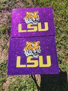 two purple and yellow lsu decals sitting in the grass