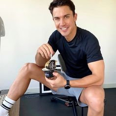 a man sitting on a chair holding a can of beer and smiling at the camera