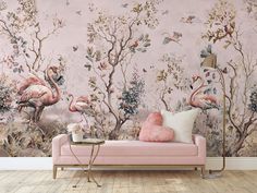 a pink couch sitting in front of a wall with flamingos and trees on it