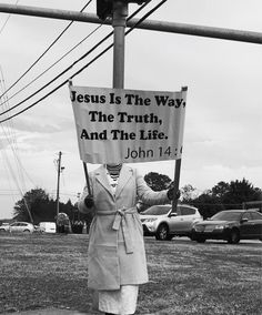 a woman holding a sign that says jesus is the way, the truth, and the life