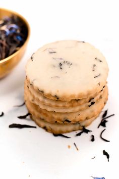 a stack of cookies sitting on top of a white table next to a bowl of tea