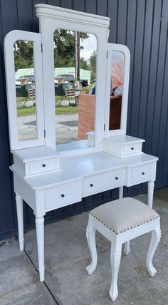 a white dressing table with mirror and stool