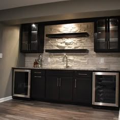 a kitchen with black cabinets and stainless steel appliance on the wall, along with dark wood flooring