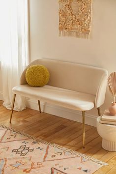 a white bench sitting on top of a hard wood floor next to a vase and lamp