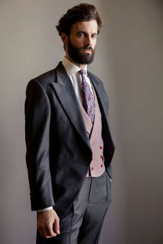 a man in a suit and tie poses for the camera with his hands in his pockets