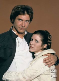 a man and woman hugging each other in front of a brown wall with the words star wars written on it