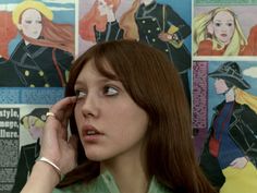 a woman talking on a cell phone in front of a wall covered with comic books