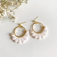 the white shell hoop earrings are on top of a flowery branch with flowers in the background