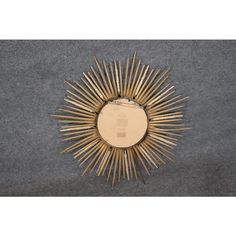 a gold sunburst mirror sitting on top of a gray carpeted floor next to a wall