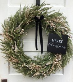 a christmas wreath hanging on a door with a merry sign attached to the front and side