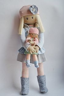 a stuffed doll holding a teddy bear in her arms