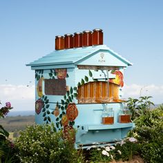 a blue building with flowers painted on the side and four jars in front of it