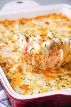 a red casserole dish with cheese and sauce being lifted from the casserole