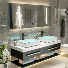 a bathroom with two sinks, mirrors and towels on the counter top in front of it