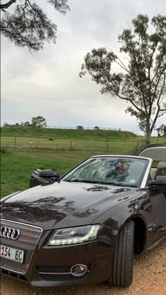 a brown car parked on the side of a dirt road