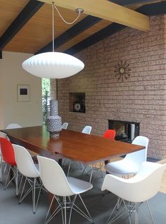 a dining room table with chairs and a fire place in the back ground, next to a brick wall